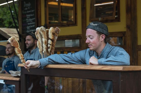 Ein Verkäufer reicht Stockbrot über eine Theke nach unten
