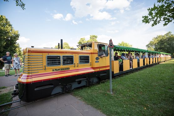 Ein großer gelber Zug fährt auf den Schienen der Killesberg-Bahn