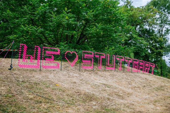 An einem Zaun klebt der Schriftzug "We love Stuttgart" des Tape-Artists André Brüggemann.
