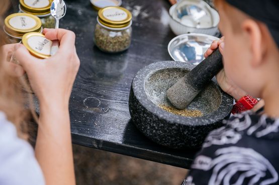 Ein Kind zermalt Kräuter in der Kräutersalz-Werkstatt der Stadtwerke Stuttgart